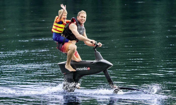 uomo e donna su Manta5 Hydrofoiler bici elettrica sull’acqua in movimento su lago